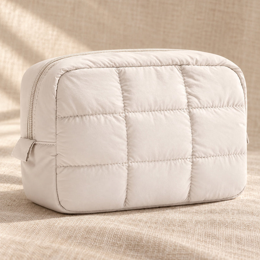 Ivory quilted puffy makeup pouch on sand linen