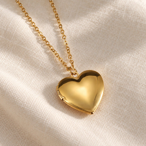 Gold heart photo locket necklace on ivory linen